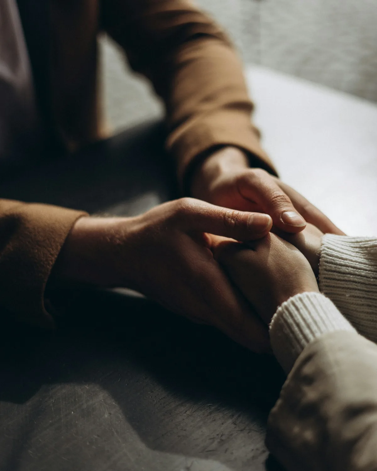 Een hand rust troostend op de hand van een ander