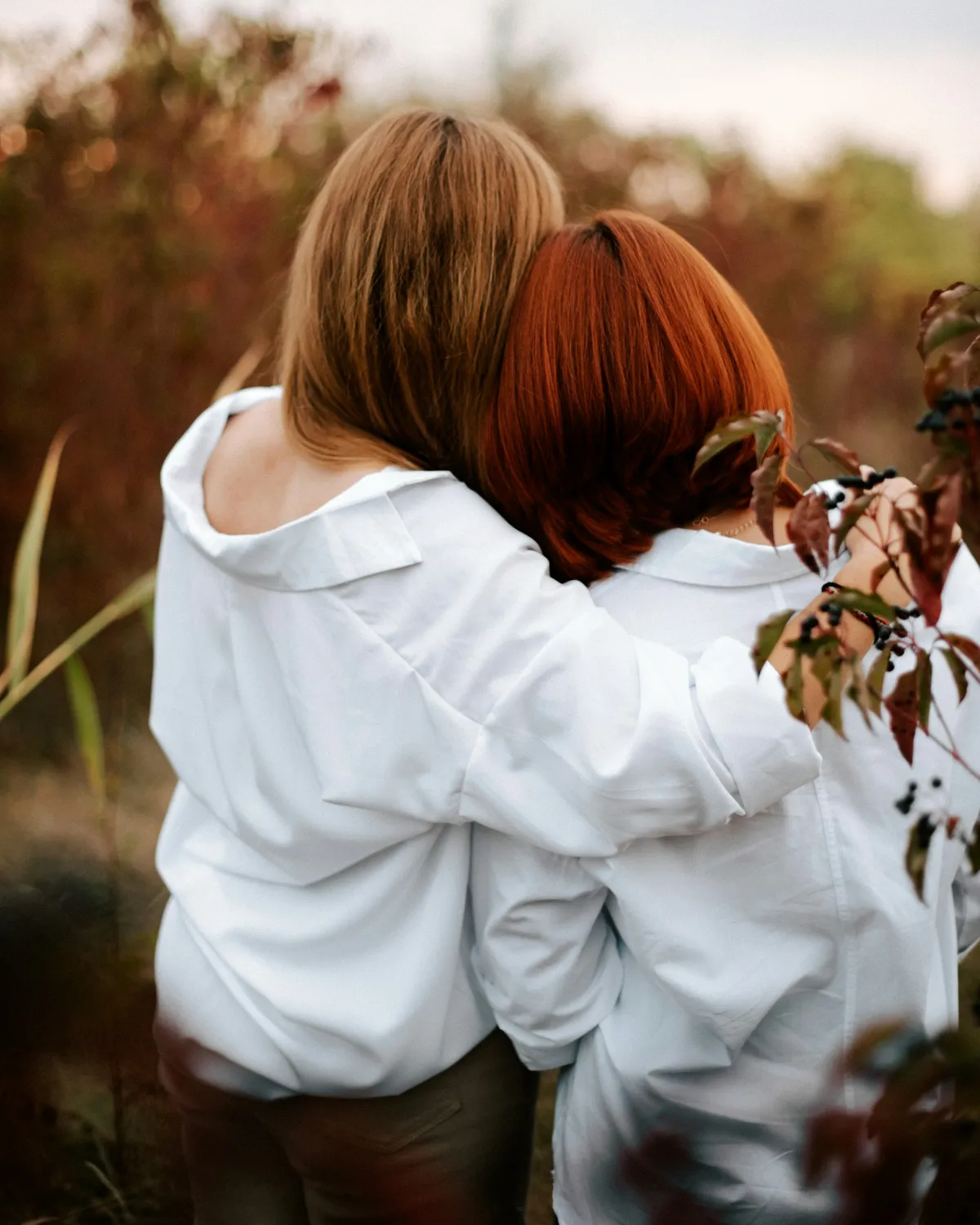 Twee vrouwen houden elkaar vast, van achteren gezien, in warm avondlicht